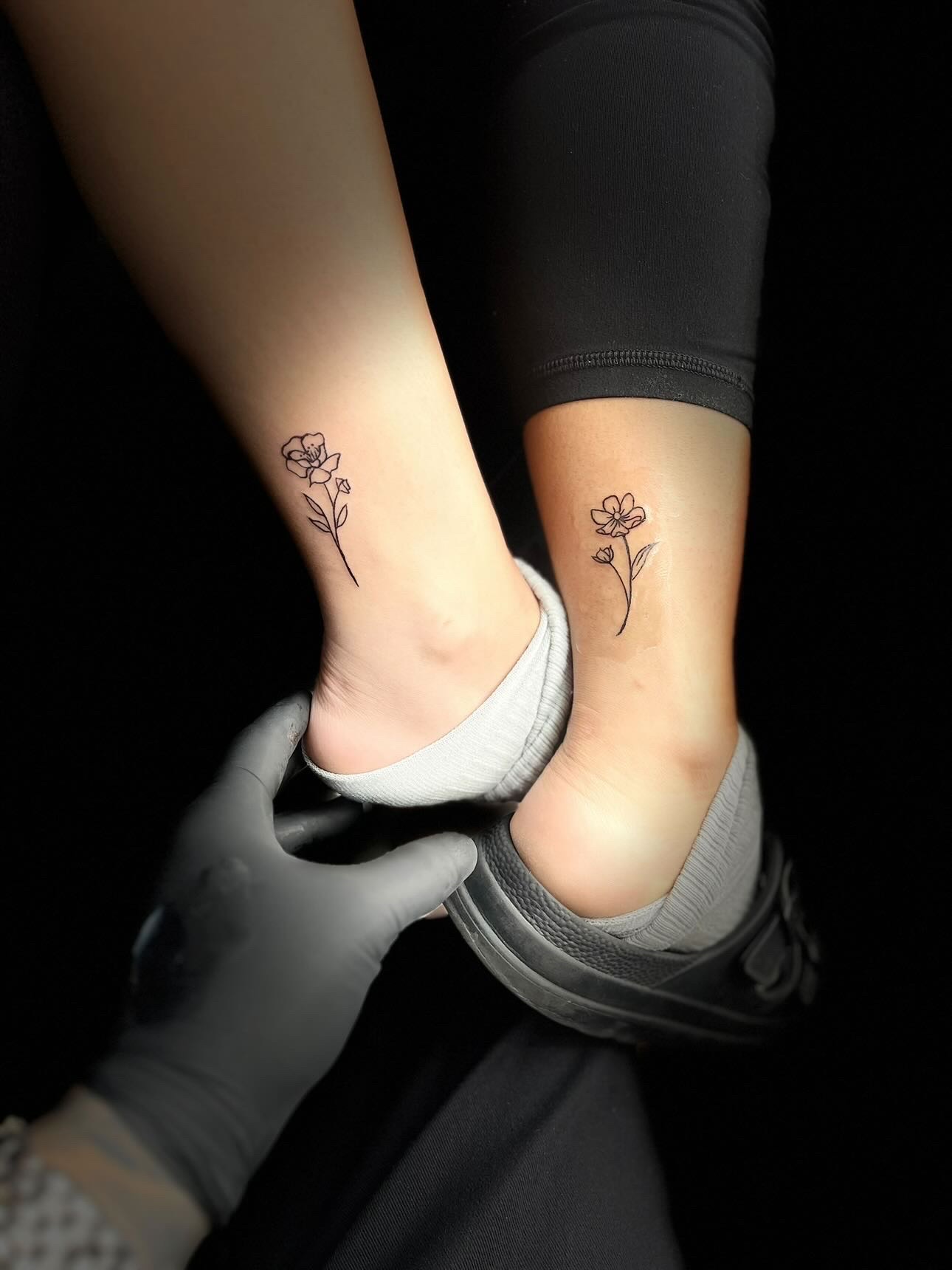 Fine line flower tattoos on ankles